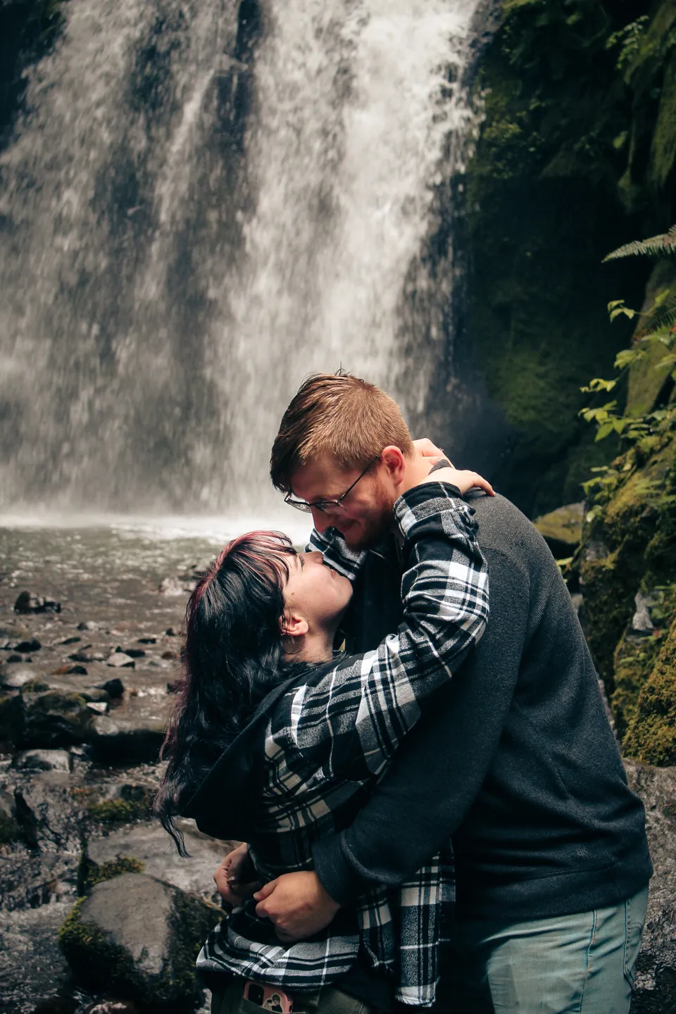 An embrace beside a woodland waterfall